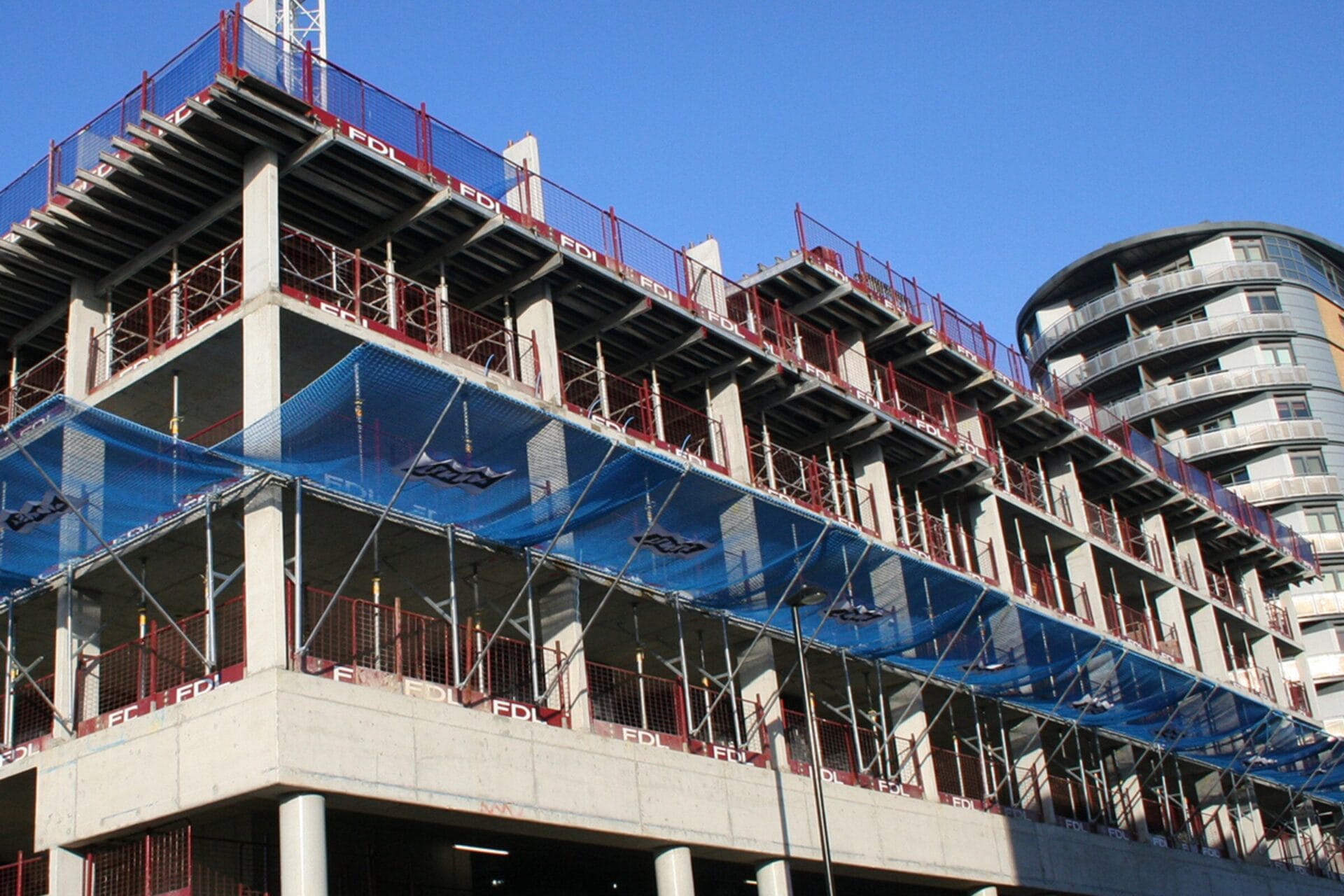 Materialauffangschirme Absturzsicherung: Materialauffangschirm angebracht an einer Baustelle